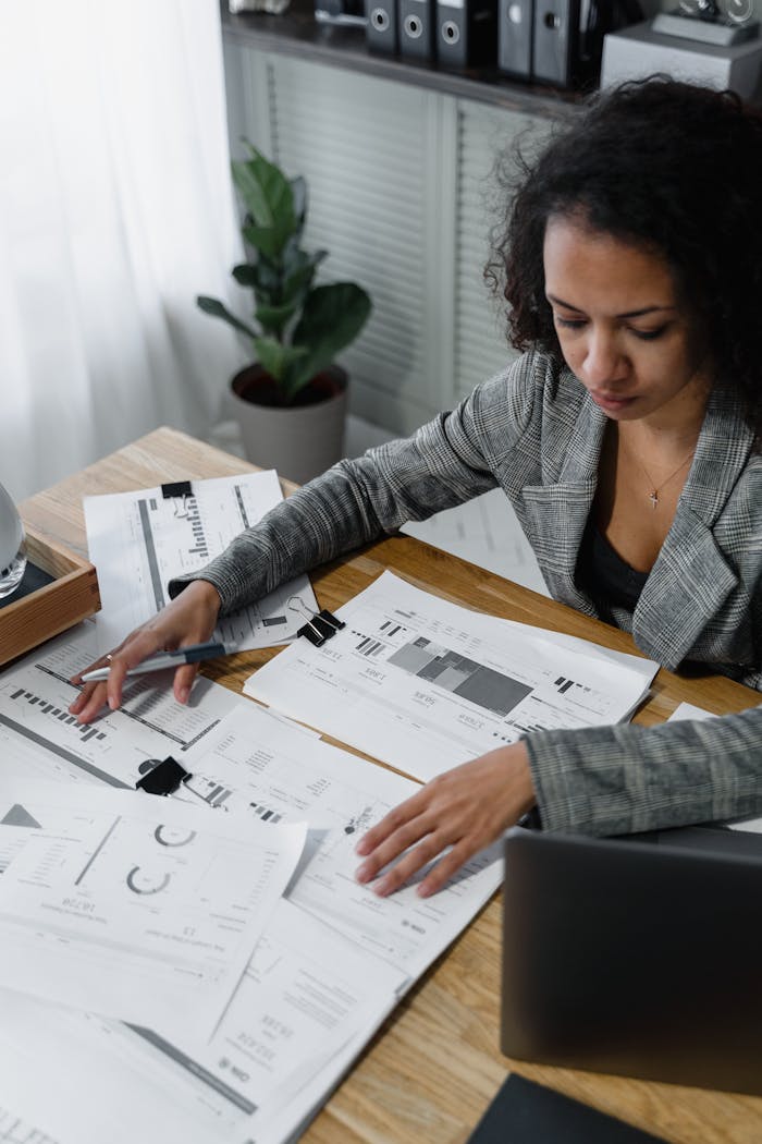 Professional woman reviewing documents and charts at a desk in a modern office.